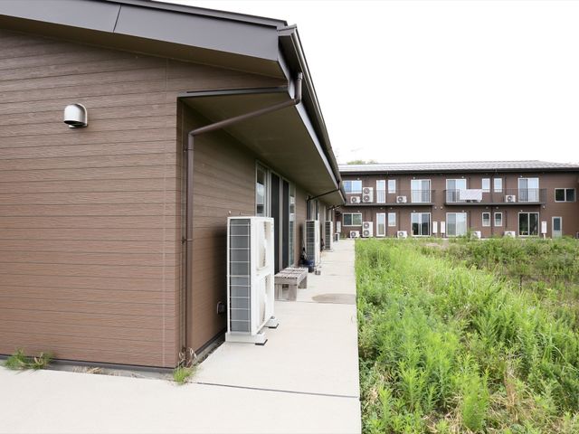茶色の外壁の建物外観 外観 ゆったりと歩ける外廊下が特徴の建物です。周囲の自然と調和した設計で、穏やかな日々を過ごせる環境が整っています。