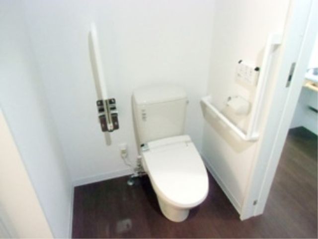 バリアフリーのトイレ設備 トイレ 手すりが設けられ、清潔感のあるトイレ空間です。安全で使いやすさに配慮された設計は、就業を考える際の重要なポイントです。