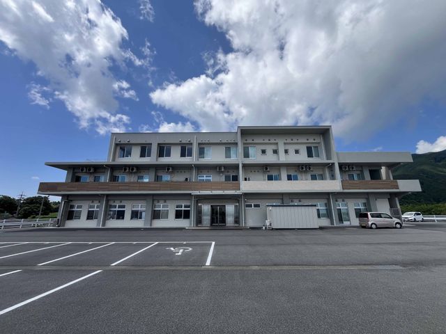 広々とした建物の外観 外観 広々とした駐車場を備えた建物です。青空の下で明るい印象を与えます。