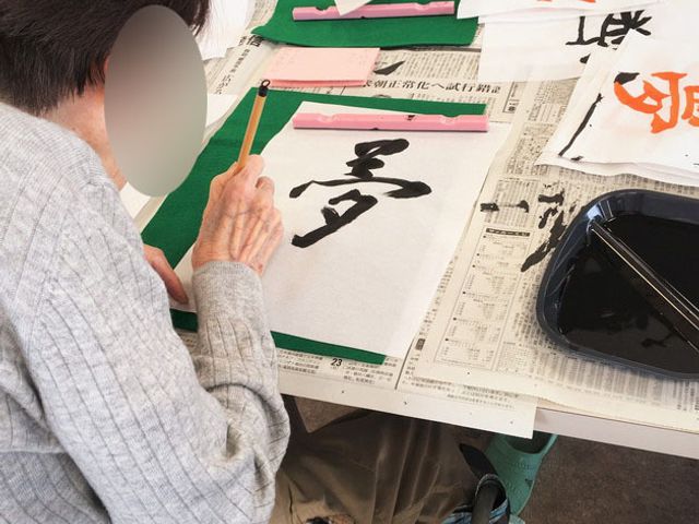 書道を楽しむ利用者達 多目的室 ゆったりとした空間で、利用者が書道を楽しんでいます。リラックスした時間が流れています。