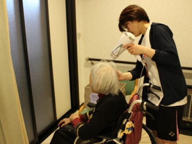 スタッフイメージ スタッフイメージ スタッフが利用者の髪を乾かす様子です。親身なケアが感じられるシーンです。