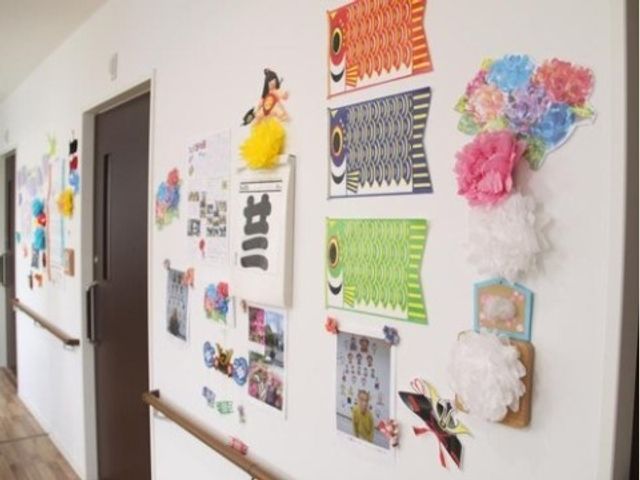 壁に飾られた手作り作品 お飾り 手作りの作品で彩られた廊下は、温もりを感じさせ、訪れる人々にやすらぎを提供します。日々の生活に創造的な刺激を与え、豊かなコミュニケーションの場となっています。