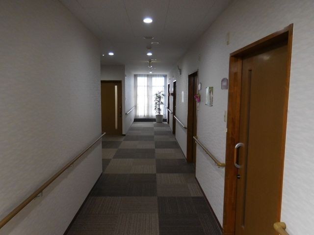 明るく広々とした廊下 廊下3 ぬくもりを感じる木目のドアが並ぶ、ゆったりとして静かな通路です。ここでの仕事は落ち着いた環境で行えるでしょう。