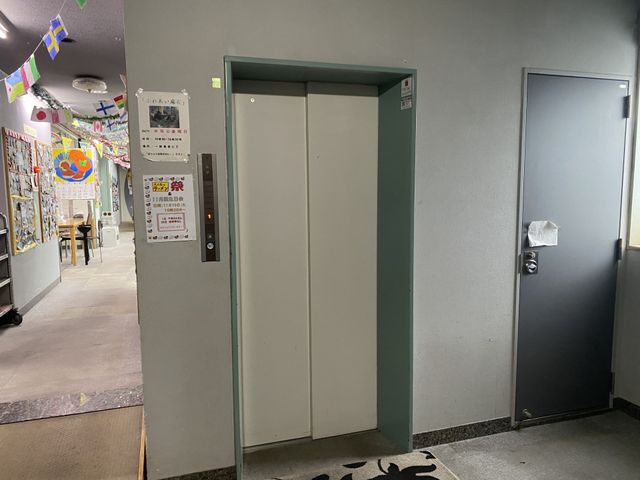 エレベーター前の廊下 廊下 シンプルなデザインのエレベーターが設置されています。周囲に掲示物があり、活気を感じます。