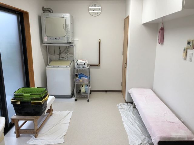 洗濯と休憩の部屋 コインランドリー 洗濯機と乾燥機が完備されたスペースで、洗濯作業も快適に行えます。奥には休息用のベンチもあります。