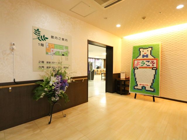 案内板とアートの玄関 入口 心地よいエントランスには、案内板とカラフルなアートが飾られており、来訪者を温かく迎えます。