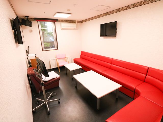 赤いソファのある休憩室 娯楽スペース 赤いソファが並ぶくつろぎスペースです。壁掛けのテレビでリラックスしながら時間を過ごせます。