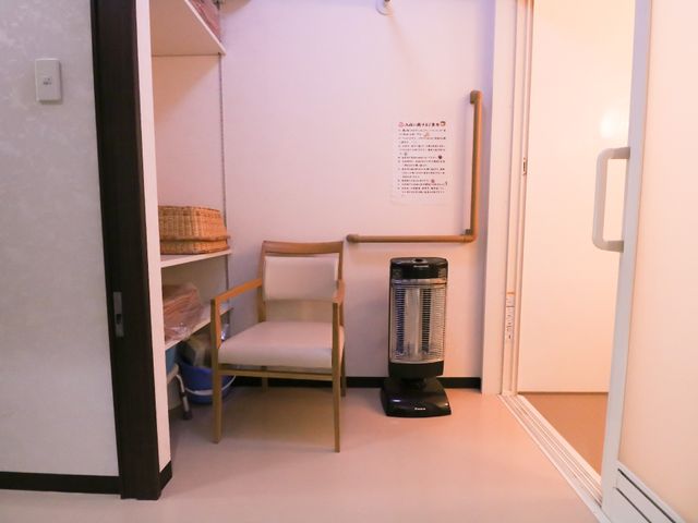居室の一角と物置 シニアライフ 居室には必要な物を収納する棚があり、快適な空間作りが工夫されています。手すりの設置もあり、安心して生活できる配慮がされています。