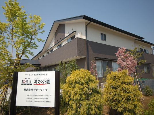 新緑と桜のある建物外観