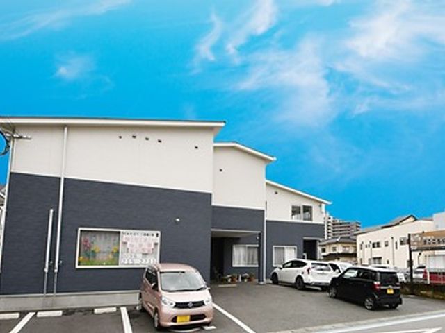明るい外観の施設 外観 広々とした駐車スペースがあり、アクセスがしやすい環境です。青空に映える清潔感のある建物です。
