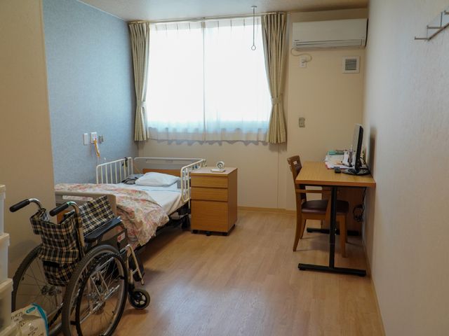 居室と車椅子の様子 居室 ゆとりある造りの居室です。個々のニーズに合わせた家具配置で、快適に過ごせる空間が整っております。