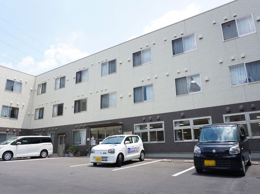 白い壁の建物と駐車場