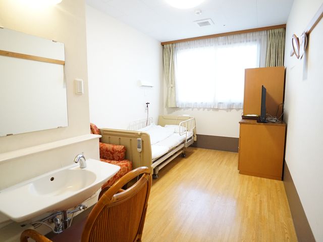 快適な居室の一角 居室 ゆとりある居室には必要な家具が整い、プライベートな時間を快適にお過ごしいただけます。白い窓枠からは自然な光が差し込み、温もりを感じる空間が広がっています。
