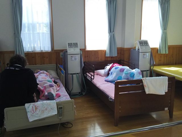 居室の日常風景 居室 ゆったりとした居室で、看護師が一対一でケアを行っています。窓辺の明るさが心地よい空間を演出しています。
