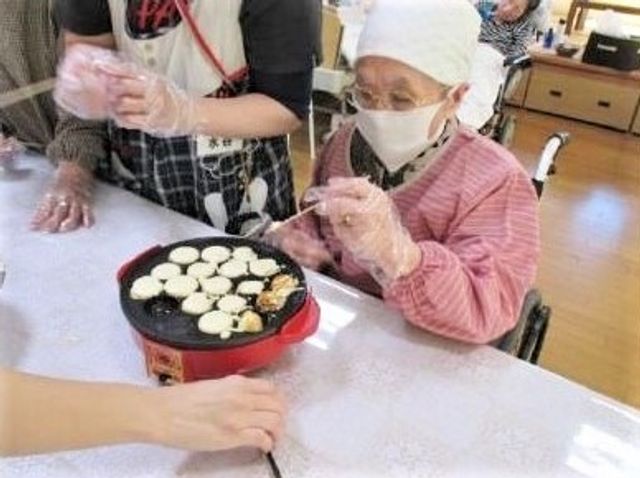 料理活動をする利用者 レクリエーション 笑顔で料理に取り組む利用者の様子です。手作りのおやつ作りを通じて、楽しい時間を過ごしていらっしゃいます。