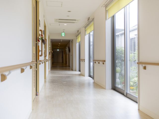 大きな窓の廊下 廊下 自然光を取り入れた明るい通路です。手すりが設置され、安全に歩行できます。