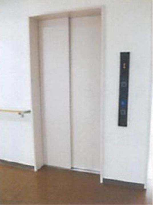 白い壁で茶色のフローリングの通路には手すりが設置されている。各階移動用にはエレベーターもあり便利である。