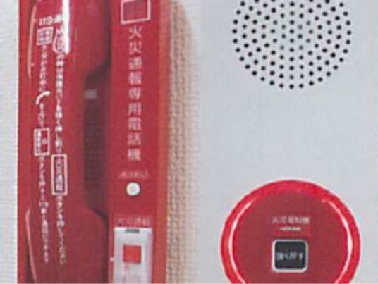 火災通報装置の赤色の受話器とボタンである。ボタンをおすと消防署に自動音声で通報され、折り返しかかってきたら受話器で応答する。