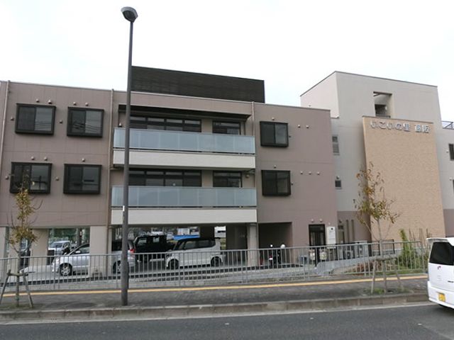 モダンな外観の建物 外観 エントランスの周りは広々としており、アクセスしやすい造りになっています。駐車スペースも十分にあります。