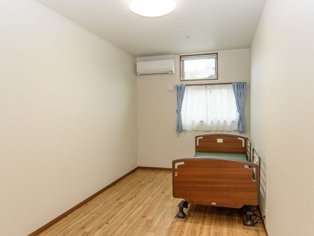 居室のベッドと窓 居室 明るく清潔な居室です。窓からの自然光が心地よく、快適な時間をお過ごしいただけます。