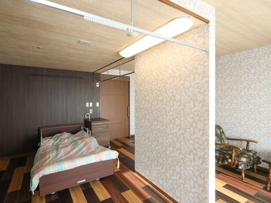 天井には、カーテンレールが取り付けられており、ベッドの部屋を隠すことができる。ベッドの右側には、木製の棚が置いてある。