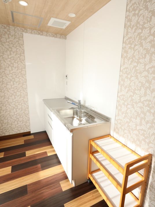 部屋の隅に、シンクがありシンクの下には収納棚が付けられているその右側には、小さなラックが置いてある。