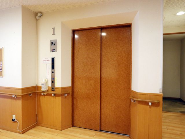 茶色の扉のエレベーター エレベーター アクセスしやすい位置に設置されたエレベーターです。壁と調和する落ち着いた色合いが特徴です。