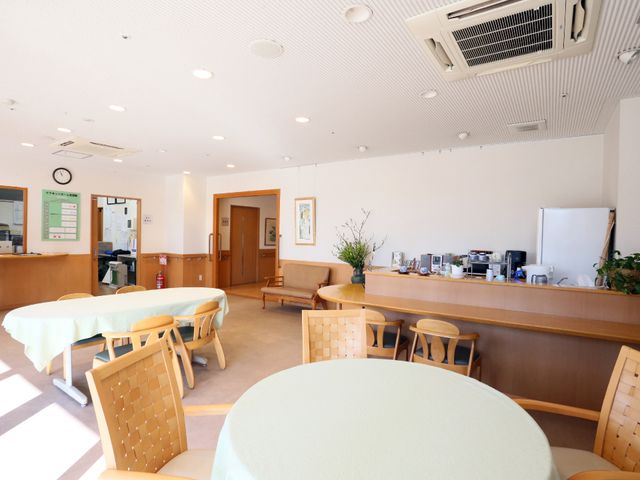 居心地の良い食堂 エントランス らくらく椅子に座れるゆったり食堂です。壁には時計や掲示物があり、家庭的な雰囲気を醸し出しています。
