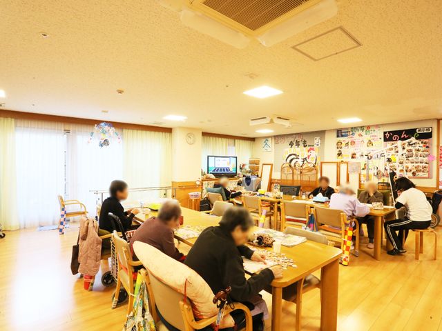 明るい活動中の共有スペース リビング さまざまな活動に彩られた広々とした共有スペース。職員とのコミュニケーションやレクリエーションを楽しむ姿が見られます。