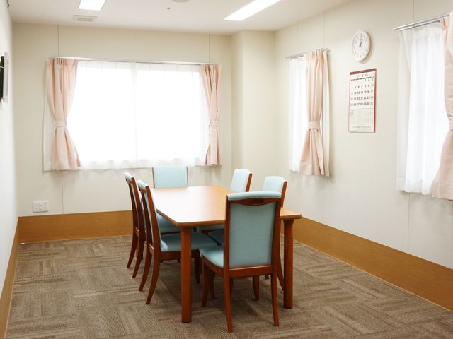明るいダイニングテーブル 共有スペース ゆったりとしたダイニングルームで、利用者の皆さんが食事や会話を楽しむ姿が想像できます。窓からの自然光で、居心地の良い空間が広がっています。