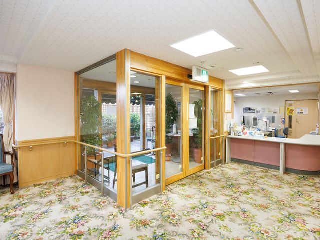 木製ガラス扉と受付カウンター 受付 広々とした空間の受付エリアです。ガラス張りの木製扉が温かみのある雰囲気を醸し出しており、訪れる方を優しく迎えます。