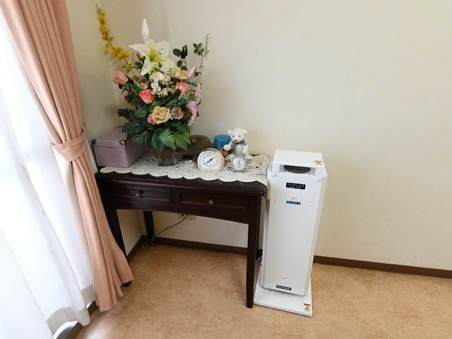 居室の装飾と空気清浄機 居室 心温まるディテールが施された居室の一角です。空気清浄機が置かれ、清潔で快適な環境が保たれています。