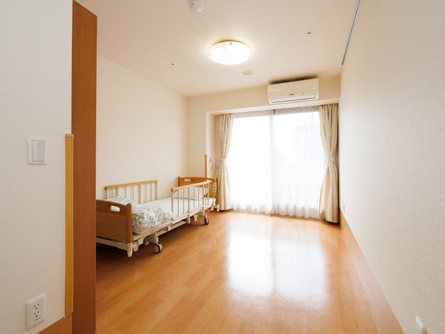 明るい居室の様子 居室 清潔感あふれる個室で、落ち着きのある木目と柔らかな光が心地良い空間を提供しています。窓からの採光が部屋を一層広々と感じさせます。