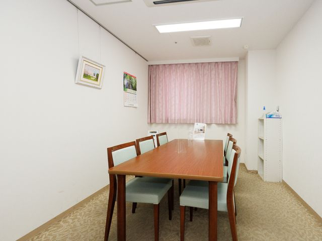 清潔な居室のダイニングテーブル 談話室 ゆったりとしたダイニングスペースで、安らぎある食事の時間を提供しています。シンプルで明るい装飾が心を落ち着かせます。