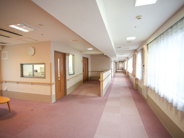 廊下の明るい空間 廊下 手すりが備わり、歩行に配慮された廊下です。壁には掲示物があり、通路は清潔で開放感があります。