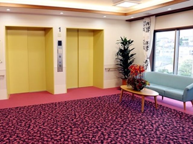 エレベーターホールの明るい空間 談話コーナー ゆったりとしたエレベーターホールは、植物とアートで彩られ、落ち着いた雰囲気を提供しています。ソファが配置され、待ち時間も快適に過ごせるよう配慮されています。