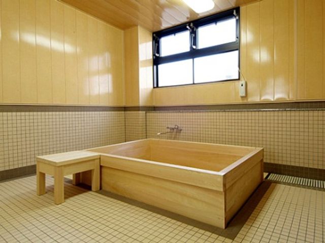 木製の浴槽と椅子 浴室 清潔感のあふれる浴室で、ゆったりとした入浴時間をお過ごしいただけます。安全に配慮された設計で皆さまをお迎えいたします。
