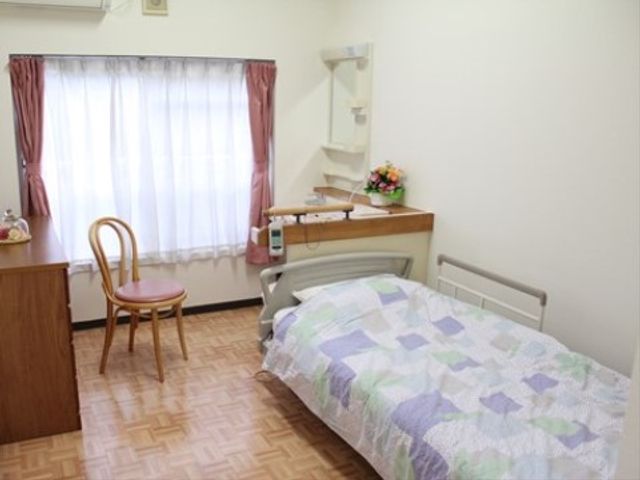 明るい単身用居室 居室 ゆったりとした床面積の個室で、日当たりの良さが印象的です。機能的な家具と明るい窓辺が安らげる環境を提供しています。