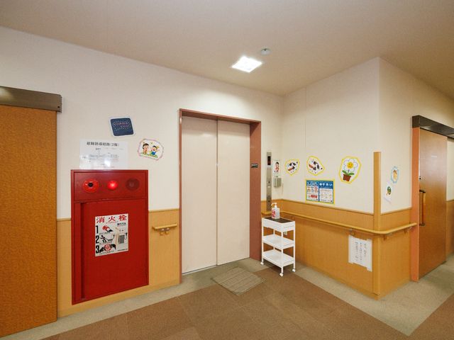 廊下の明るい様子 エレベーター 清潔感のある廊下は、壁には彩り豊かな掲示物が飾られ、訪れる方々への心遣いが感じられます。