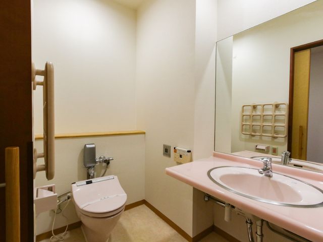 清潔感のあるトイレ空間 トイレ バリアフリー設計のトイレは、手すりが備わり安全性が考慮されています。快適で清潔な環境を支える仕事に関心がある方に適しています。