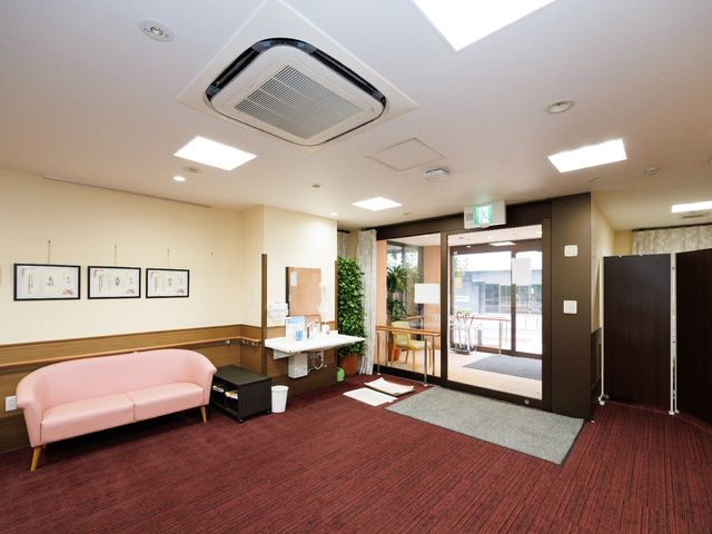 エントランスの明るい空間 心地よい空気が流れる入り口で、待合のピンクのソファが歓迎する様子が伝わります。訪れた方の快適な待ち時間を想像させます。