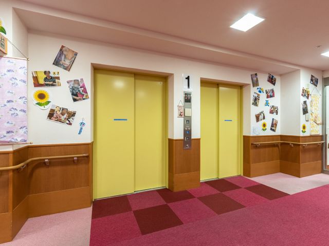 カラフルな廊下のエレベーター エレベーター 手すり付きで安全を考えた明るい廊下です。壁に飾られた写真が温かい雰囲気を醸し出しています。