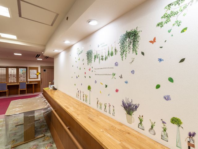壁に描かれた花と緑の装飾 廊下 温かみのある空間を提供するロビーです。壁面の花や緑のイラストは、訪れる人々の心を癒す工夫が施されています。
