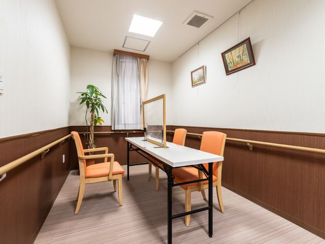 落ち着いた雰囲気の休憩室 共有スペース ゆったりとした椅子と机が配置された休憩室です。壁には絵が掛けられ、窓から自然光が差し込んでいます。