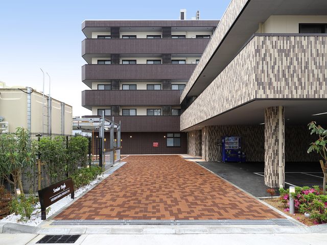 モダンな建物のエントランス アプローチ ゆったりとした通路を備えた洗練されたデザインのエントランスです。来訪者を温かく迎える明るい雰囲気が感じられます。