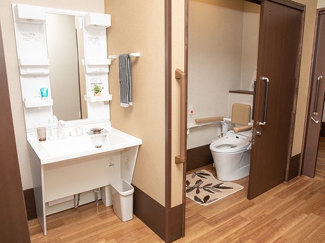洗面台とトイレのある廊下 トイレ   手すり付きのトイレと洗面台が並ぶ、使いやすい空間です。木目調の床で落ち着いた雰囲気になっています。