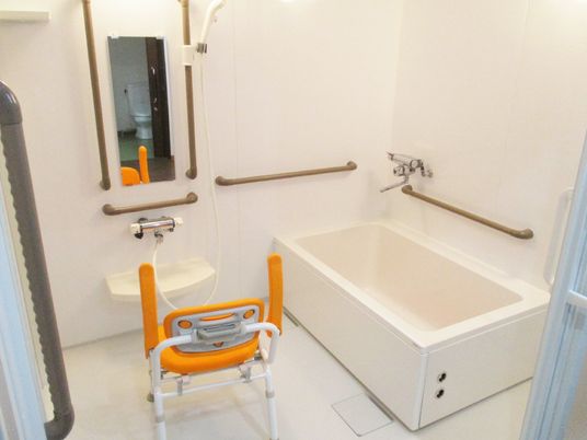 施設の写真 一人用の浴槽が設置された浴室。シャワーやシャワーチェアもあり、手すりが壁についている。