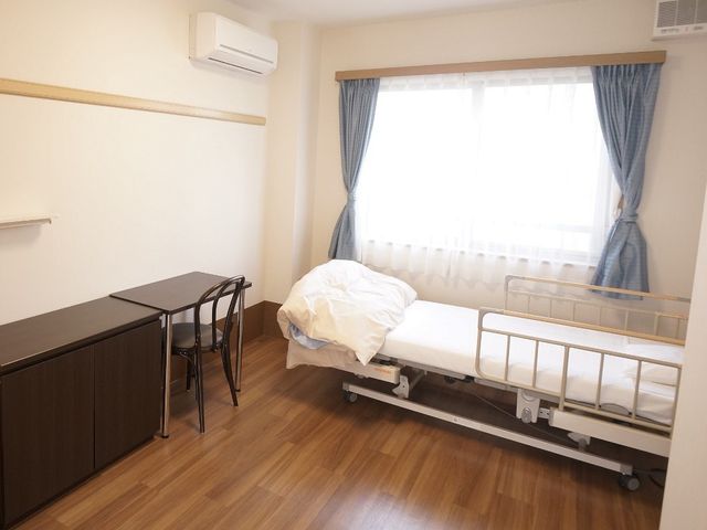 落ち着いた雰囲気の居室 居室 広々とした室内にベッドや机が配置され、明るい自然光が差し込む快適な空間です。