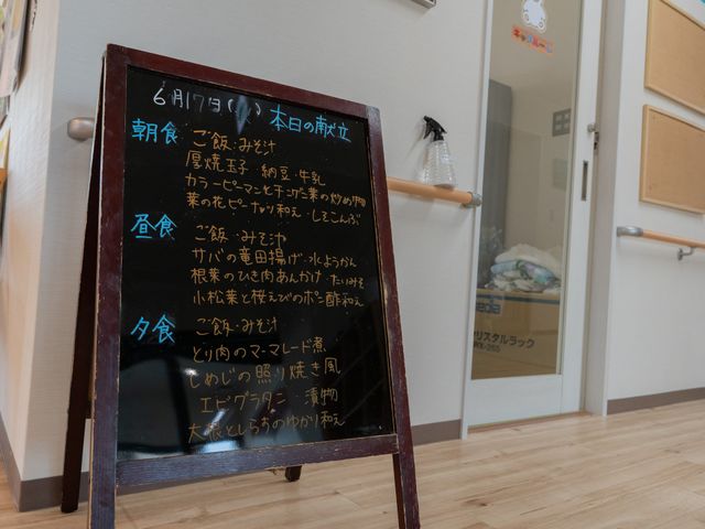 案内板が置かれた廊下 廊下 案内板には、本日の献立が丁寧に書かれています。移動しやすい広さの廊下に設置されています。