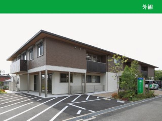 角地の外観 外観   2階建ての建物が角地に建ち、周囲に駐車スペースが見えます。落ち着いた色合いで、出入りしやすい印象です。
